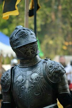 a man dressed in armor standing next to a flag