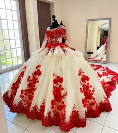 a red and white wedding gown on display in a room with large mirror, mannequin