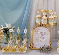 a table topped with cupcakes and cakes covered in frosting next to flowers