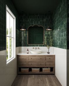 a bathroom with green tiles on the walls and wood flooring, along with a white sink