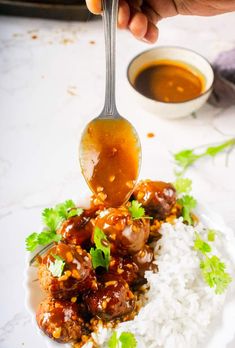 someone is spooning sauce over some food on a plate with rice and cilantro