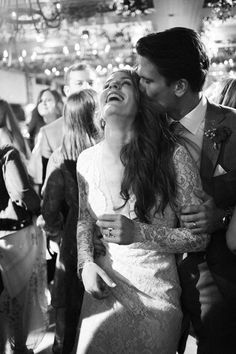 black and white photograph of a bride and groom kissing in front of a group of people