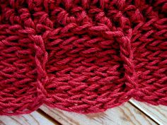 a red knitted dishcloth sitting on top of a wooden table next to a pair of scissors