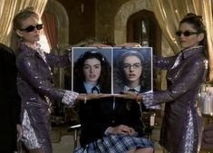 three women in dresses holding up an image of the same woman with glasses on her face