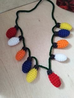 a crocheted necklace with multicolored beads on a wooden table next to yarn balls