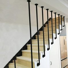 there is a set of stairs with black railings on each side and white walls