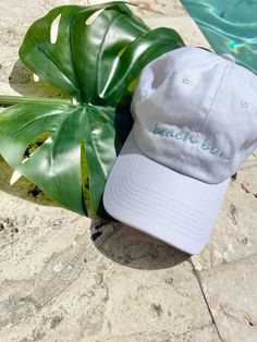 Beach bum dad hat. White dad hat, unstructured. 100% cotton, adjustable closure. One size fits most. Embroidered words in light blue. Trendy Cotton Baseball Cap For Vacation, Trendy Dad Hat Baseball Cap For Vacation, Trendy Dad Hat With Curved Brim For Beach, Trendy Curved Bill Dad Hat For Beach, Cotton Trucker Hat For Vacation, Trendy Cotton Hat For Vacation, Trendy Cotton Dad Hat For Vacation, Beach Baseball Cap With Embroidered Logo, Cotton Dad Hat With Curved Brim For Beach