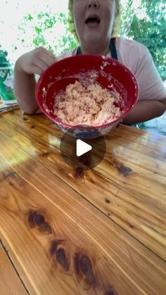 a woman sitting at a table with a bowl of food in front of her face