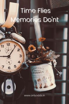 an old fashioned clock is sitting on a table next to a tin can with flowers in it