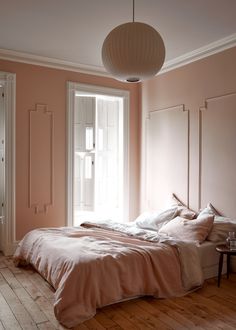 a bed sitting in a bedroom next to a window with a lamp on top of it