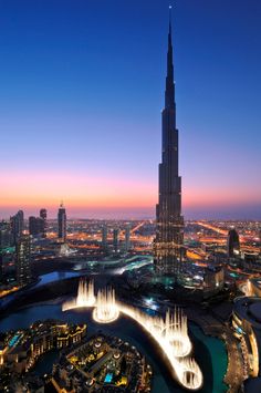 the burj tower towering over the city at night, with water fountains in front