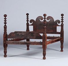 an old wooden bed frame with turned back posts and foot rests on the floor, against a white background