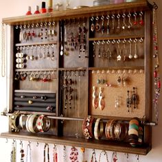 a wall mounted jewelry organizer with lots of earrings on it's sides and hanging from the ceiling