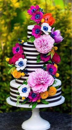 a multi - tiered cake with flowers on top is decorated in black and white stripes