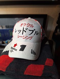 Japanese GP Driver Cap 2024 - Max Verstappen Konnichiwa, Suzuka! Make some room in your F1 cap collection and show some love for Max Verstappen at the Japanese GP with this iconic 9FORTY snapback from New Era, featuring a beautiful cherry blossom print on the crown and Oracle Red Bull Racing embroidered in Japanese on the front. A proud "1" on the visor shows everyone that you support the World Champion! Features: * Max Verstappen New Era 9FORTY Japanese GP cap * Unisex * "Oracle Red Bull Racing" embroidered in Japanese on the front crown and the team's logo patch on the back * Max's race number (1) embroidered on the visor * Embroidered New Era flag on the visor * Sponsor logos on the visor and crown * Six-panel structured crown with a cherry blossom print on the side and back panels * Em White Baseball Cap For Fan Merchandise, White Flat Bill Baseball Cap For Fans, Sporty White Baseball Cap Fan Merchandise, White Casual Baseball Cap For Fans, Casual White Baseball Cap For Fans, White Snapback Baseball Cap For Fans, White Flat Bill Hat With Graphic Print, White Baseball Cap With Curved Visor For Fans, White Hats With Letter Print For Fan Merchandise