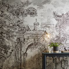 a wall with a drawing on it next to a lamp and table in front of the wall