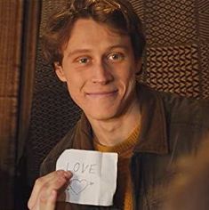 a man holding up a piece of paper with the word love written on it