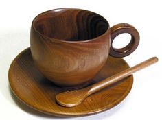 a wooden cup and saucer sitting on top of a plate next to a spoon