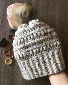 a person's hand with a knitted hat and buttons