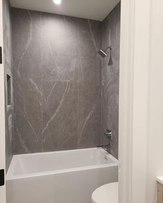 a white toilet sitting next to a bath tub in a bathroom under a ceiling light