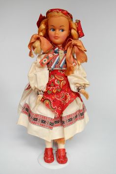 the doll is wearing a red and white dress