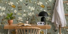 a desk with a book, lamp and birdcage wallpaper