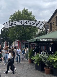 people are walking under the garden market sign