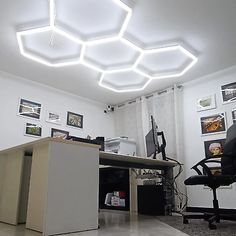 an office with a desk, computer chair and lights on the ceiling is pictured in this image