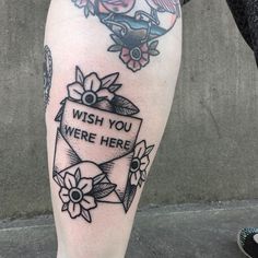 a person with a tattoo on their leg that says, wish you were here and flowers