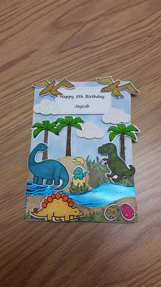 a birthday card with dinosaurs and birds on it, sitting on a table next to a watermelon