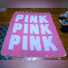 a pink towel with the words pink on it sitting on top of a wooden floor