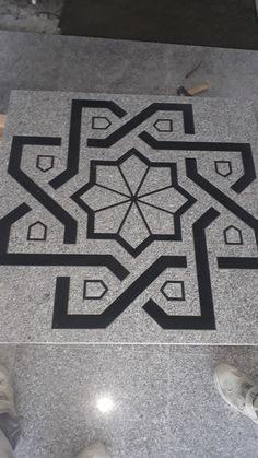 a black and white pattern on the ground in front of a person's feet