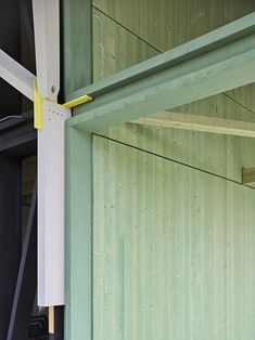 the side of a green building with yellow and white poles sticking out of it's sides