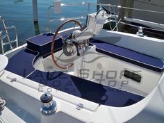 the inside of a sailboat with blue seats and steering wheel on the front deck