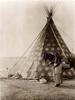 an old black and white photo of a man standing in front of a teepee