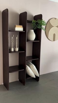 a shelf with some vases and books on it next to a wall mounted clock