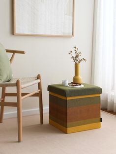 a living room with a chair, ottoman and vase on the floor in front of a window