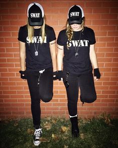 two girls wearing swagt t - shirts standing in front of a brick wall