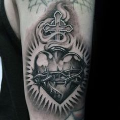 a man's arm with a cross and heart tattoo design on the left shoulder