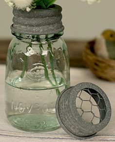 a glass jar with flowers in it sitting on a table next to a metal object