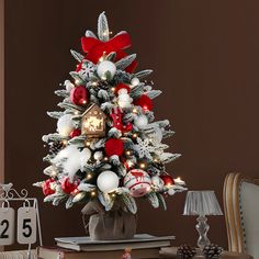 a small christmas tree decorated with red, white and silver ornaments is sitting on a table