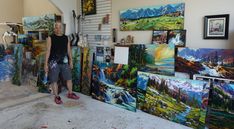 a man standing in front of paintings on the wall next to stairs and ladders