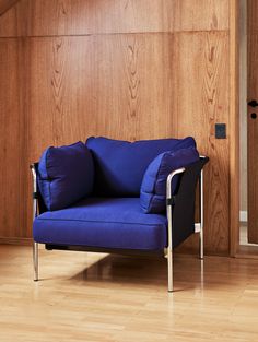 a blue chair sitting on top of a hard wood floor next to a wooden wall