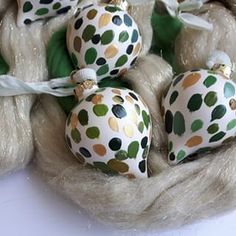 some ornaments are sitting in a basket on a tablecloth with green and gold polka dots