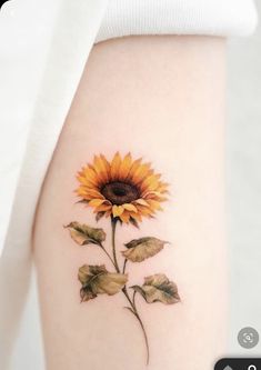 a small sunflower tattoo on the right side of the arm, with leaves around it