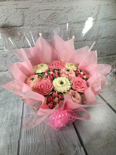 a bouquet of pink and white flowers sitting on top of a wooden table