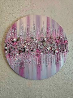 a pink and white painting on a wall with beads hanging from it's sides