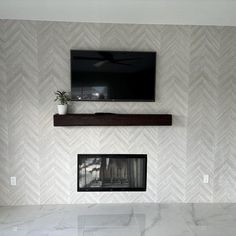 a tv mounted above a fireplace in a living room with white walls and herringbone tile