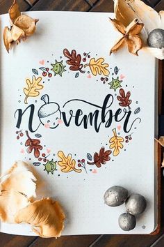 an open notebook with the word november written on it next to autumn leaves and acorns