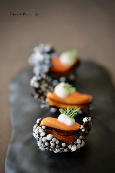 carrots and other food items are arranged on a black platter with beaded edges